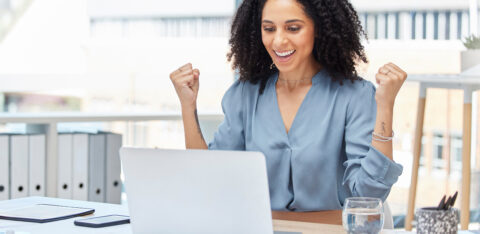 business woman celebrating winning by her computer