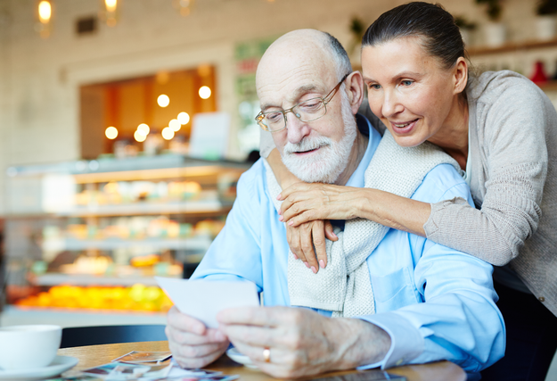 affectionate older couple looking at a note in a cafe