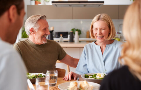 Family With Senior Parents And Adult Offspring Eating Meal Around Table At Home Together