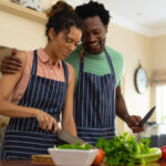 Happy young multiracial couple cooking meal together at kitchen island. people, togetherness and cooking concept, unaltered.