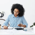 woman filing taxes with calculator and notepad