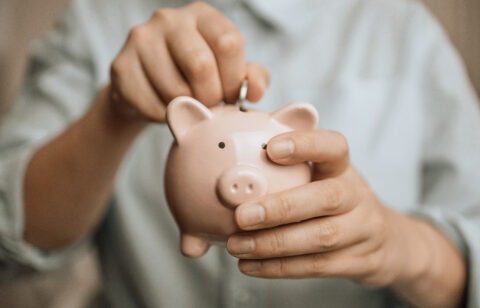 Female hands hold a pink piggy bank to save money.