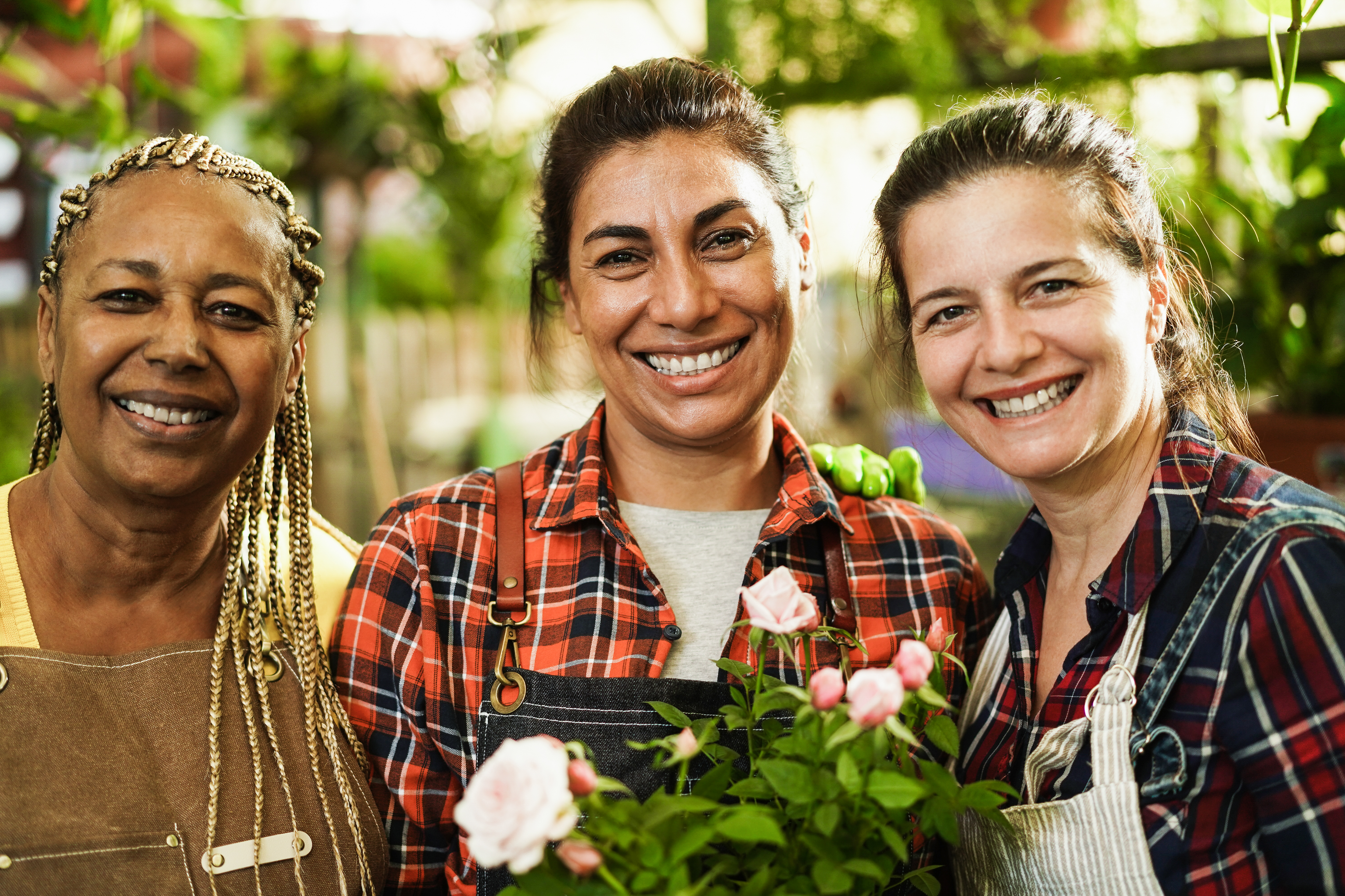 Multiracial senior women working inside greenhouse garden Focus on center female face