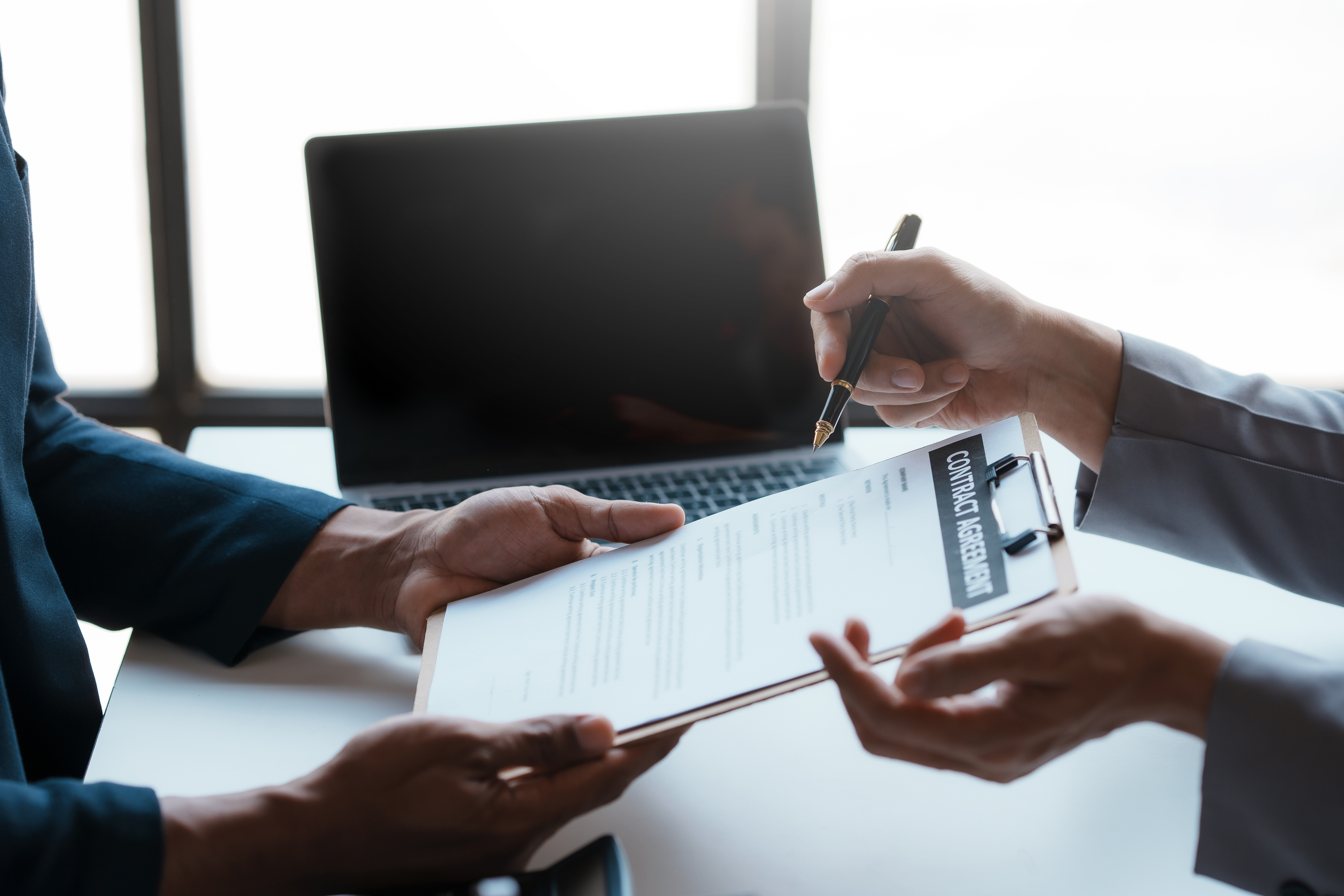 Close-up of two professionals discussing and signing a contract agreement