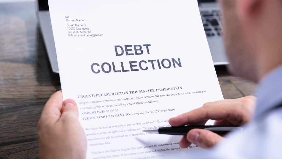 Person holding a debt collection letter while reviewing its contents with a pen in hand.