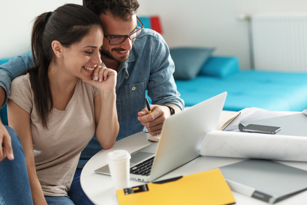 Smiling couple working on financial planning or budgeting together on a laptop.