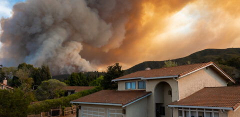 a home with smoke and flames behind it