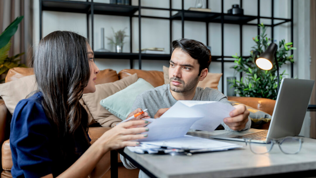 man and woman talking while looking over bills