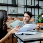 man and woman talking while looking over bills