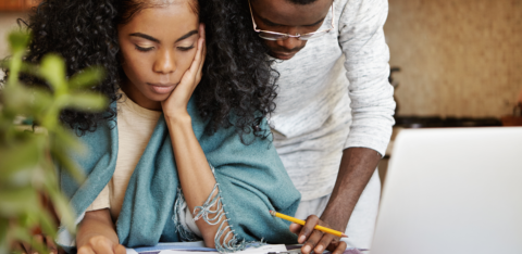 Couple reviewing financial documents together at home, looking concerned.
