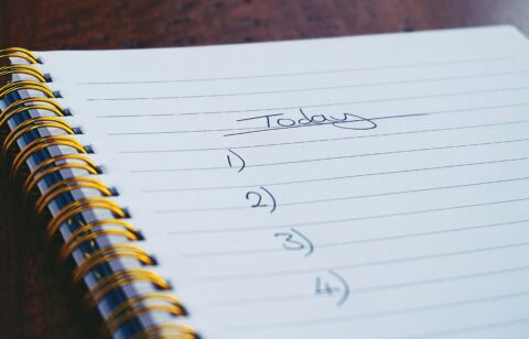 Close-up of a spiral notebook with a handwritten to-do list titled 'Today' and numbered tasks.
