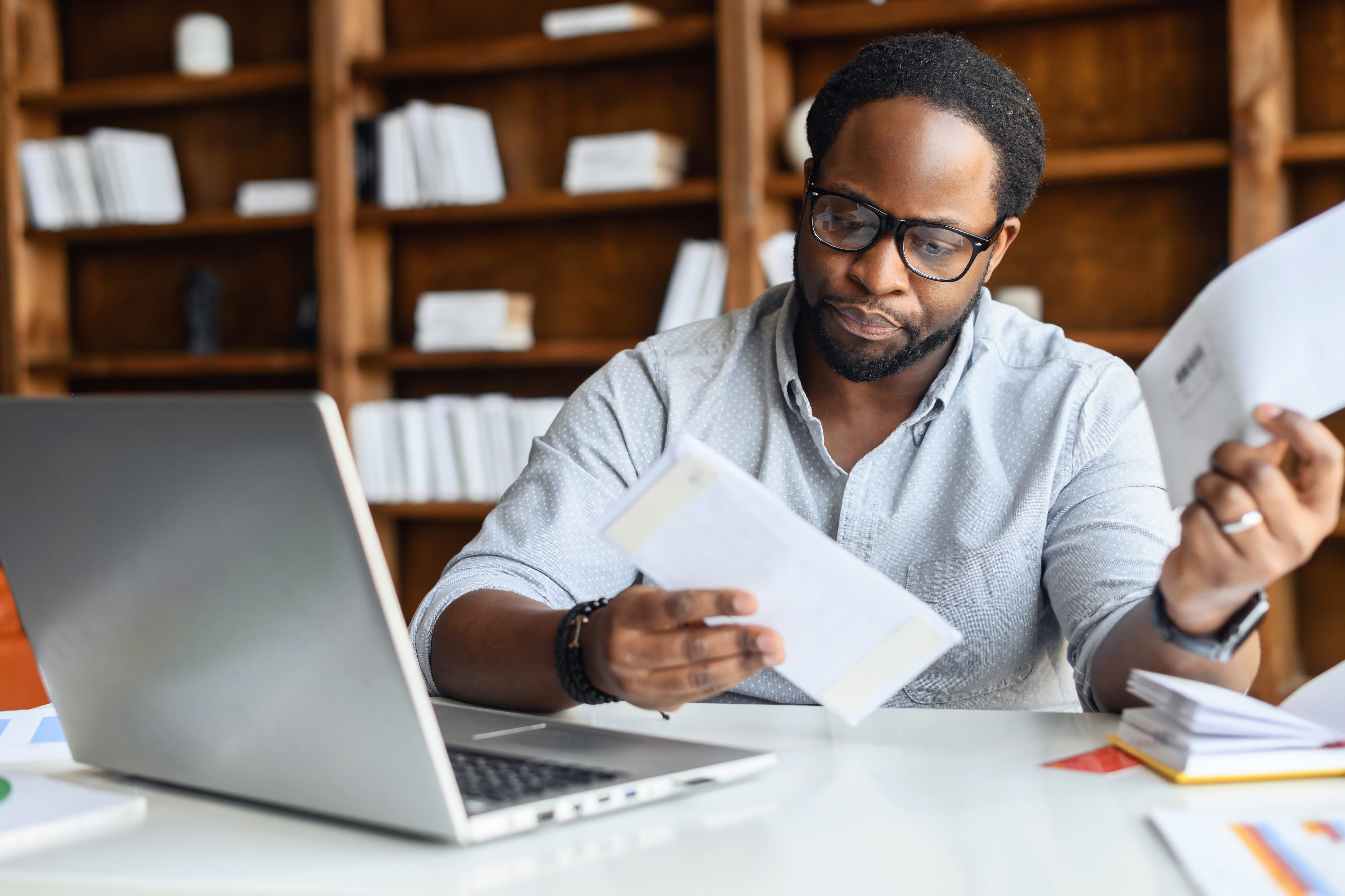 Person reviewing financial documents at a desk with a laptop and papers.
