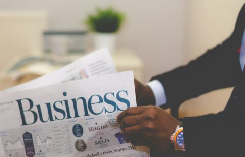 Person in a suit reading the business section of a newspaper