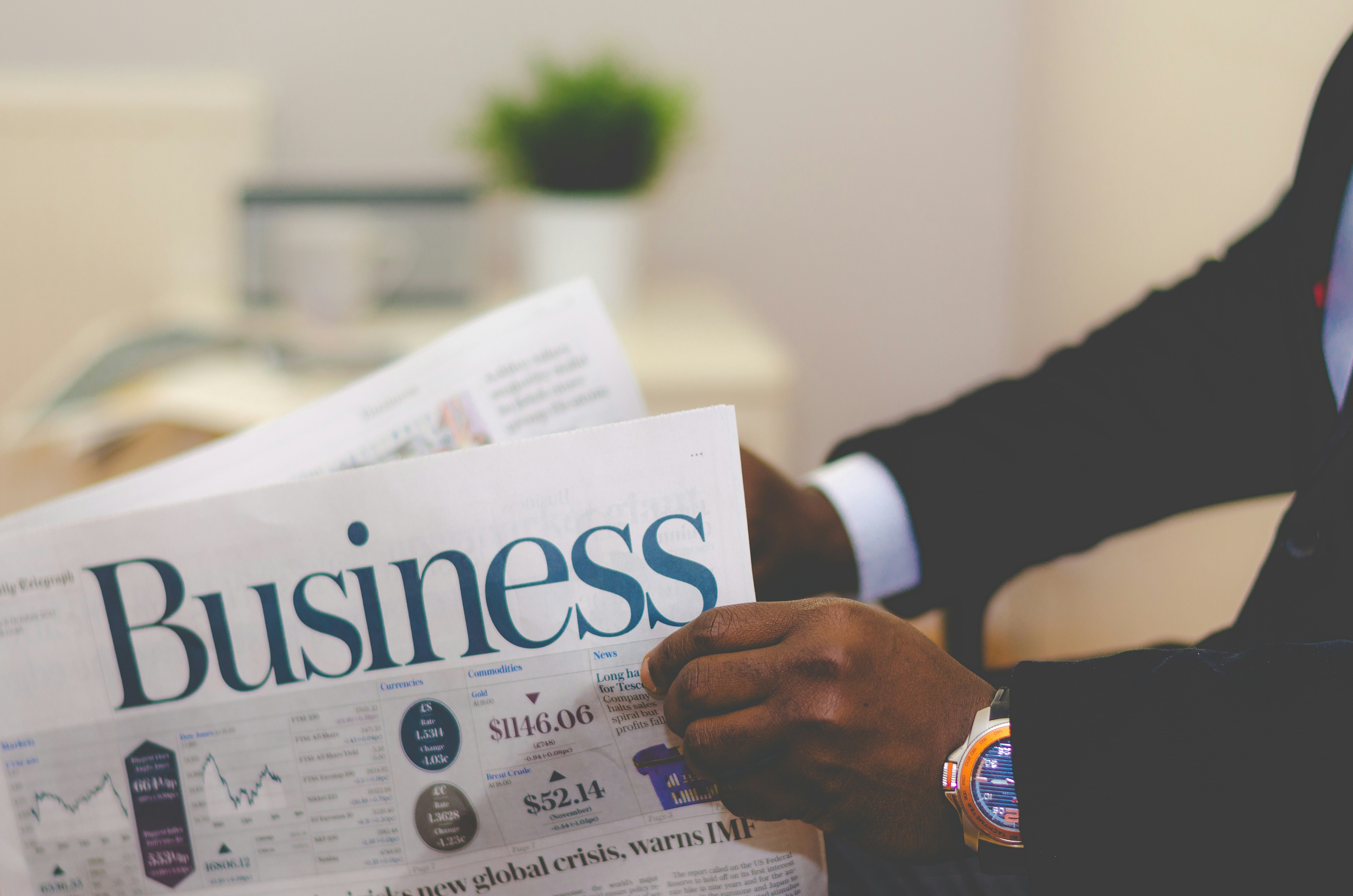 Person in a suit reading the business section of a newspaper