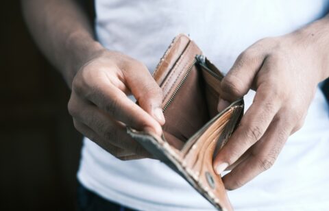Person holding an open, empty wallet with both hands.