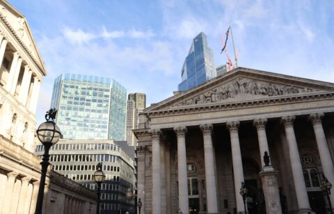 Front view of the Royal Exchange building in London, with modern skyscrapers in the background.