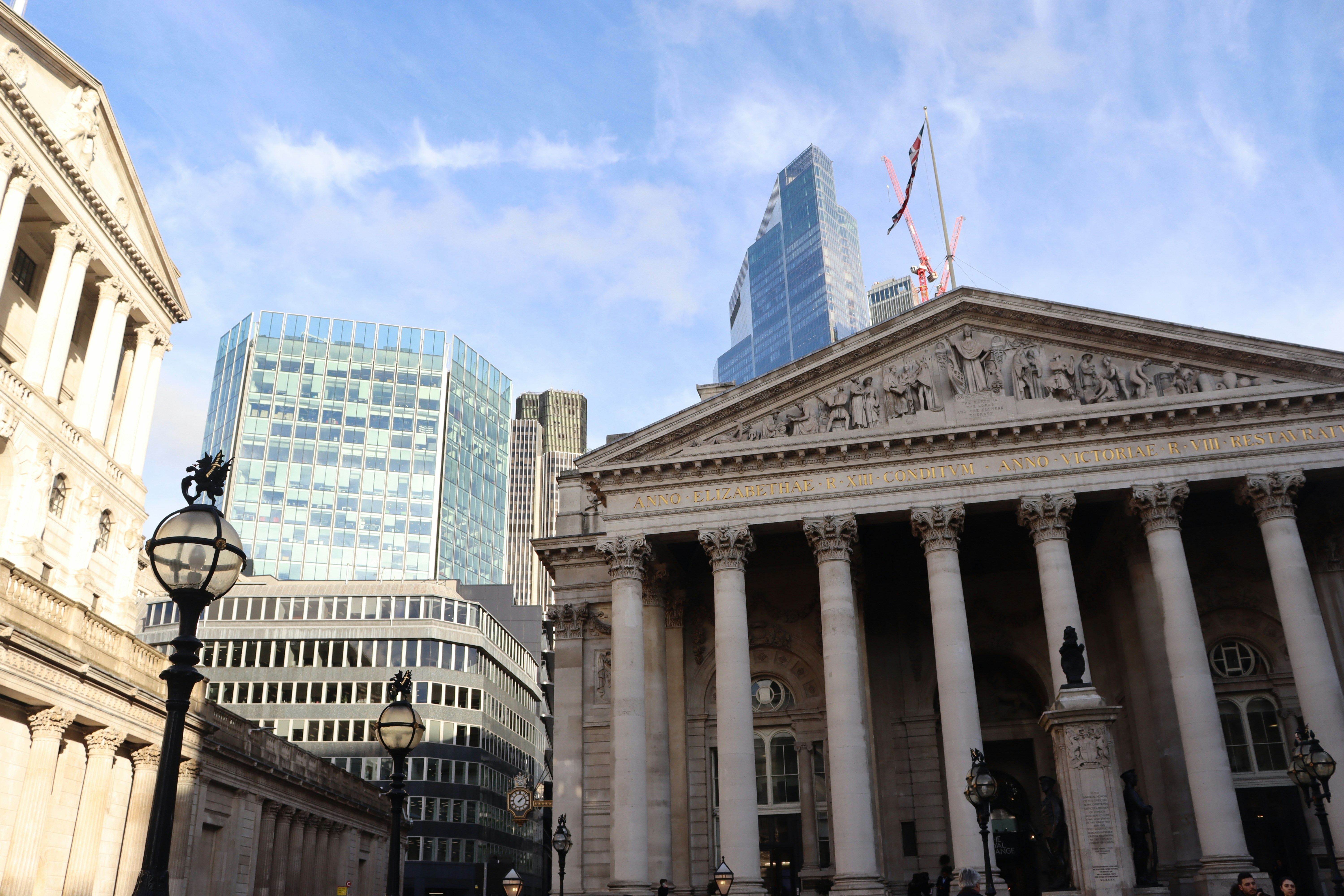 Front view of the Royal Exchange building in London, with modern skyscrapers in the background.
