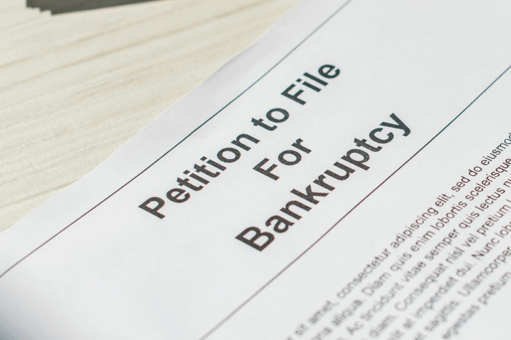 Close-up of a legal document titled “Petition to File for Bankruptcy” on a wooden desk.