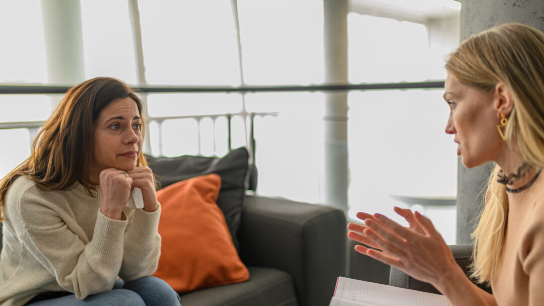 Woman receiving emotional support from a professional during a private conversation in an office setting.