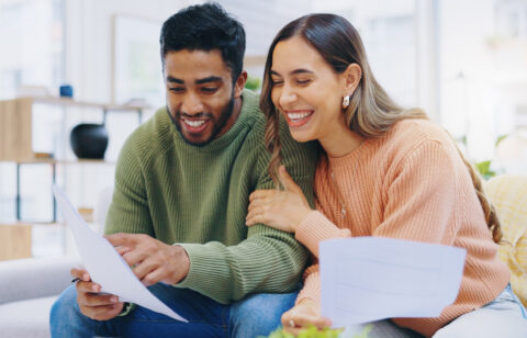 Happy man and woman looking at budgeting sheets
