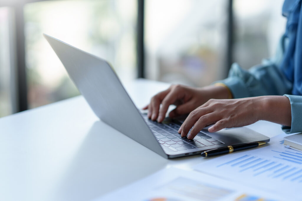 Close up of a business woman typing a laptop computer on a desk