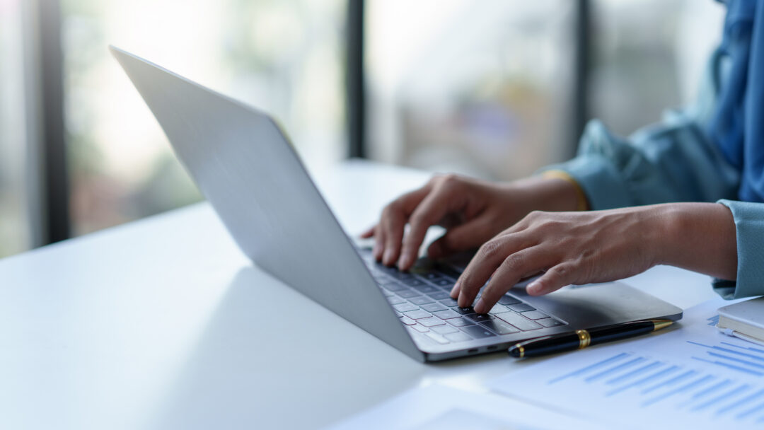 Close up of a business woman typing a laptop computer on a desk