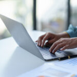 Close up of a business woman typing a laptop computer on a desk