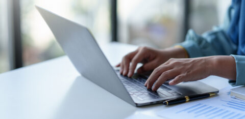 Close up of a business woman typing a laptop computer on a desk