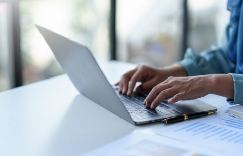 Close up of a business woman typing a laptop computer on a desk