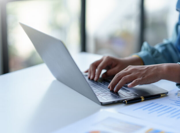 Close up of a business woman typing a laptop computer on a desk