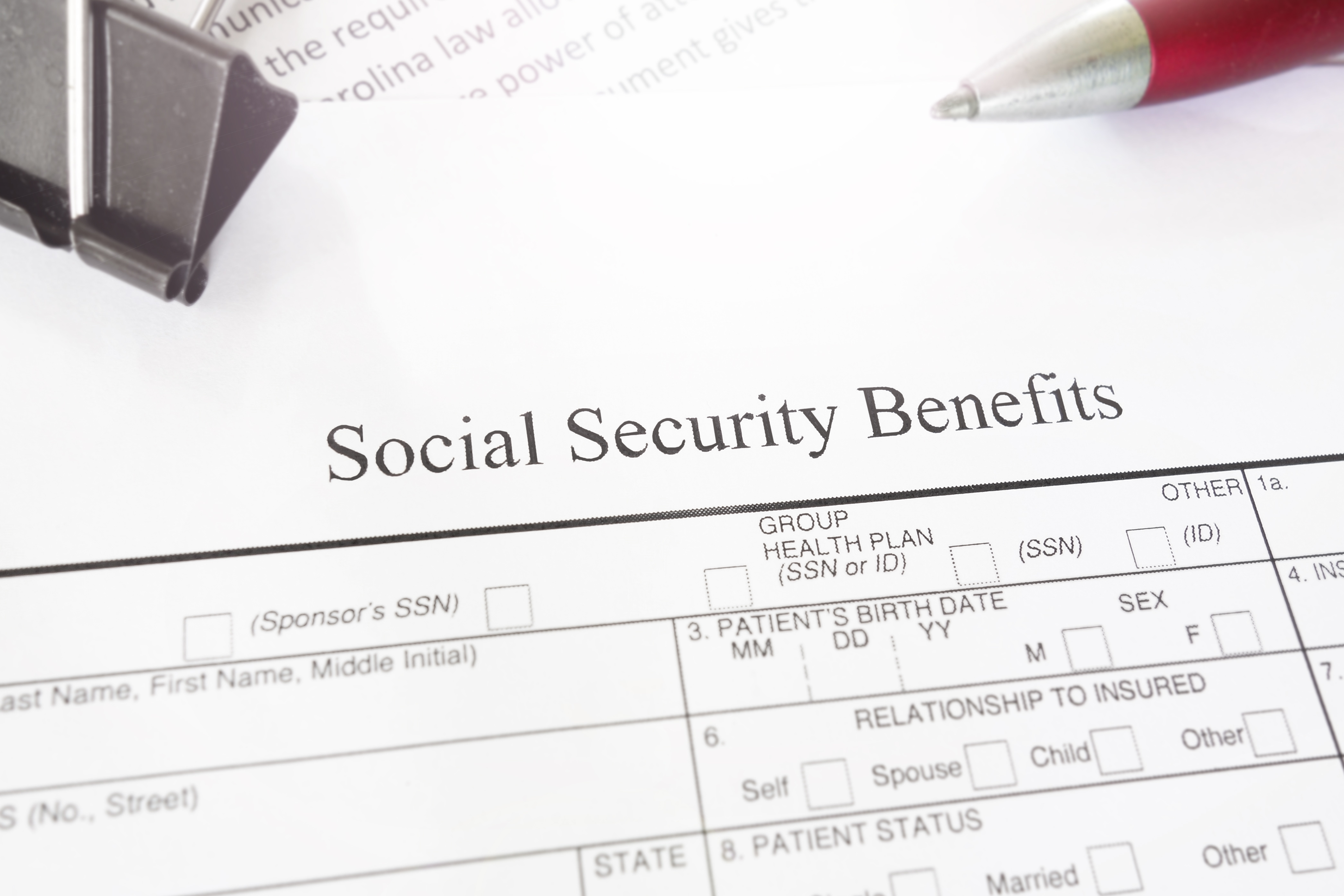 Social Security Benefits form on a desk with a red pen and paperclip.