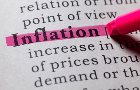 Close-up of the word βinflationβ marked with a pink highlighter on a printed page.