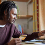 Man holding a credit card while using a laptop, focused on managing finances online.