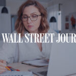Woman wearing glasses working at a laptop and taking notes at home, with The Wall Street Journal logo overlayed.