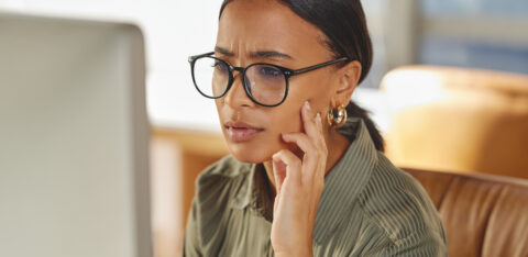 Woman wearing glasses looking intently at a computer screen.