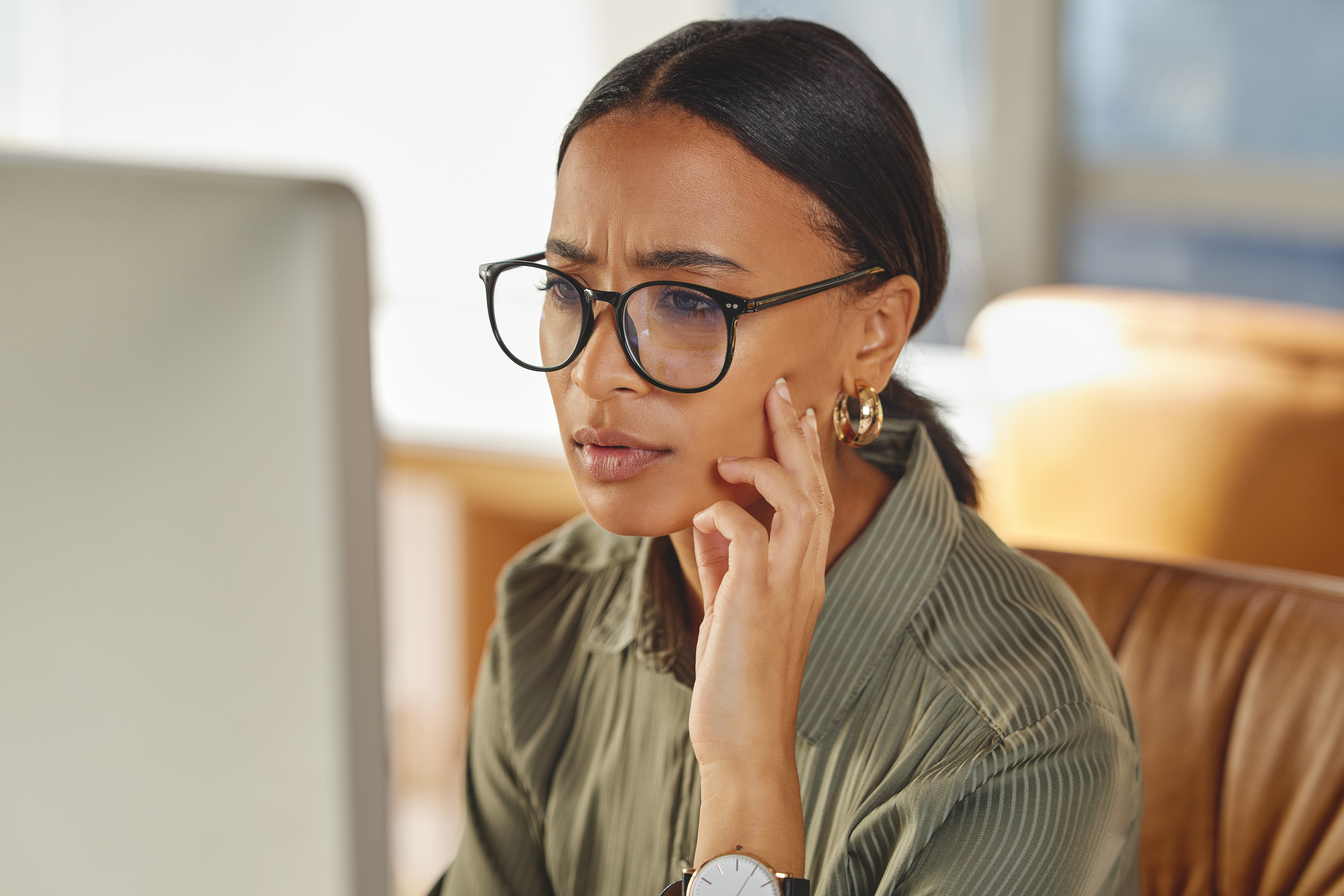 Woman wearing glasses looking intently at a computer screen.