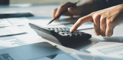 Person using a calculator to review financial documents on a desk.