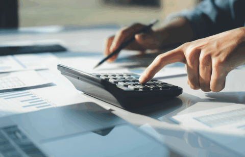Person using a calculator to review financial documents on a desk.