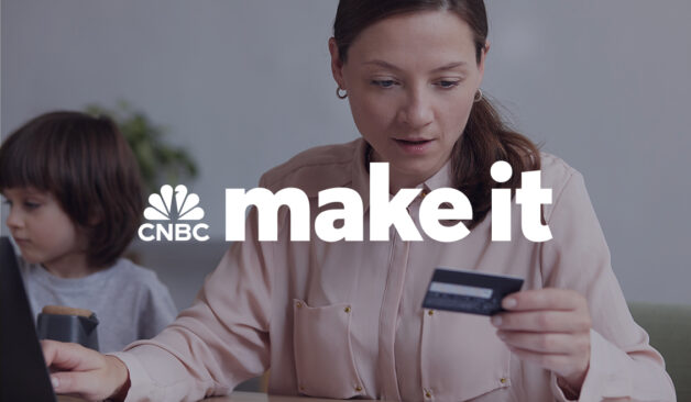 A woman holding a credit card while using a laptop, with the CNBC Make It logo overlayed on the image.