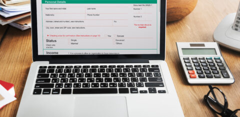 Laptop screen showing a debt consolidation loan form beside a calculator and paperwork.