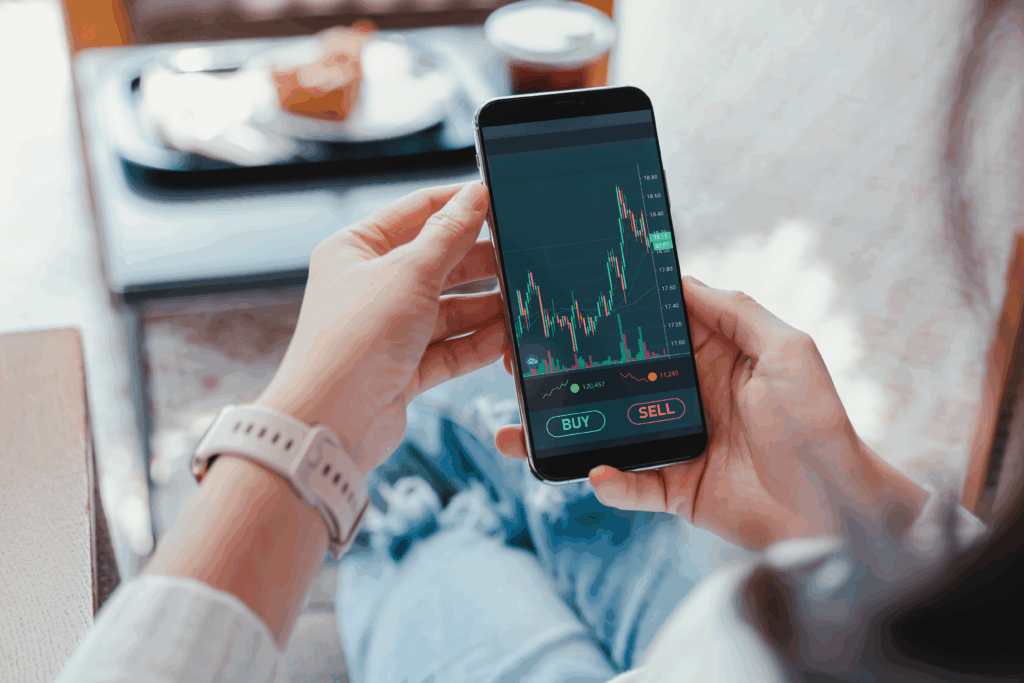Person holding a smartphone displaying a stock trading app with buy and sell options.