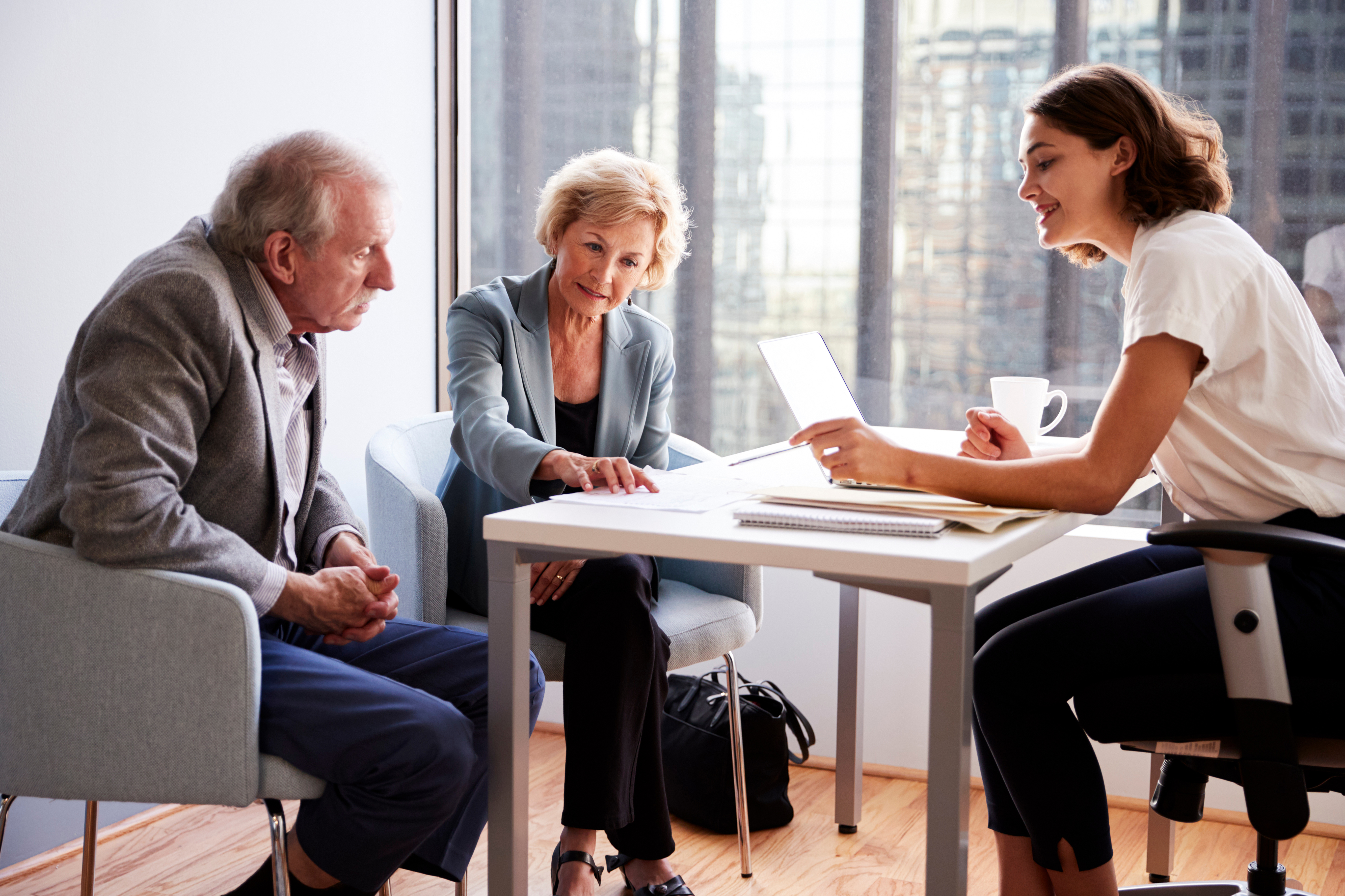 An older couple sits across from a professional in an office, reviewing financial documents together.