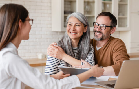 Smiling couple meeting with a financial professional at home.