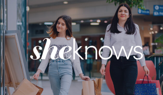 A woman and a girl smile while carrying shopping bags in a mall, with the SheKnows logo overlaid across the center.