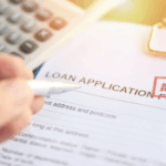 Close-up of a loan application form with an approved stamp and a hand holding a pen.