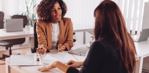 A woman meets with a professional in an office to review documents and discuss information.
