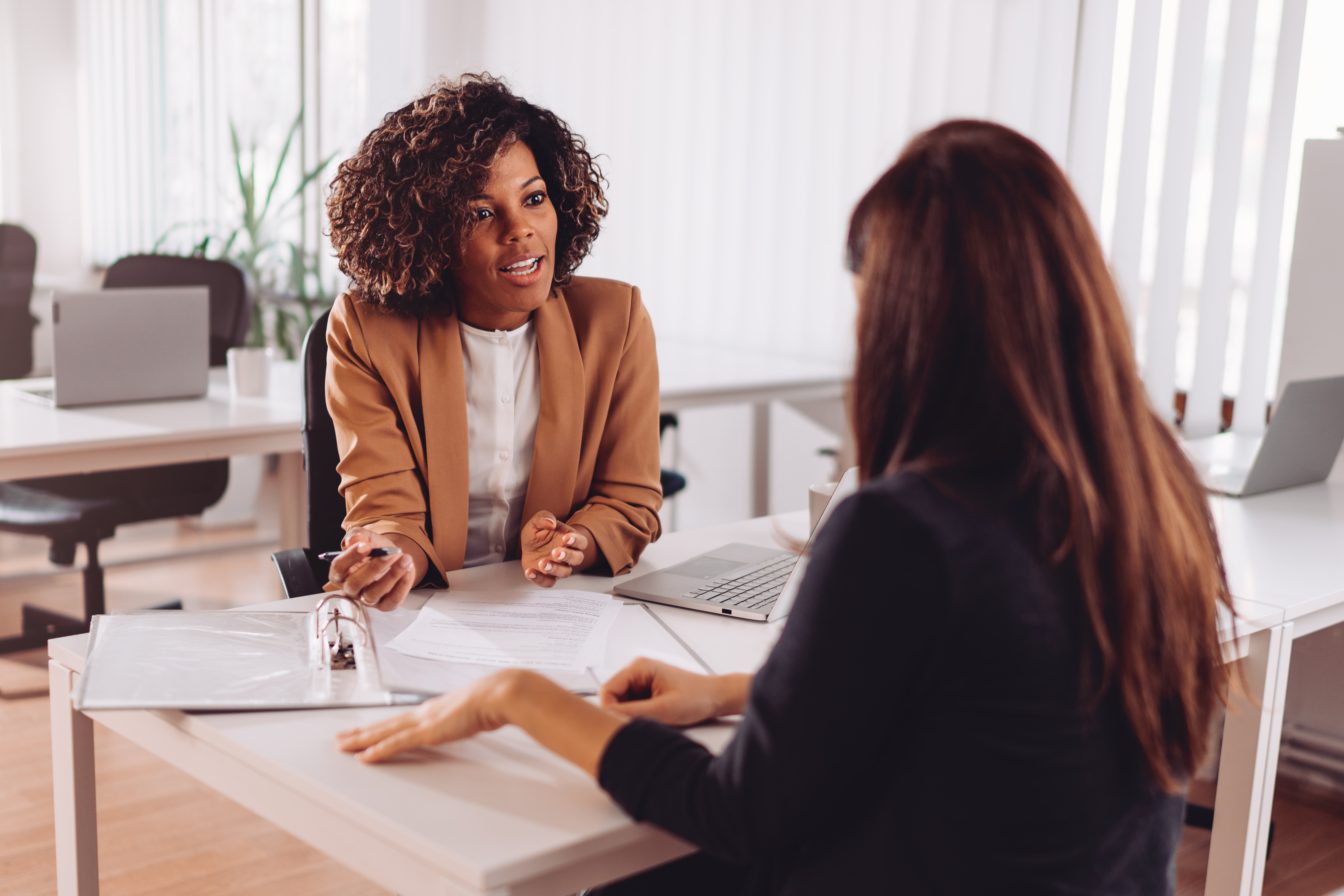 A woman meets with a professional in an office to review documents and discuss information.