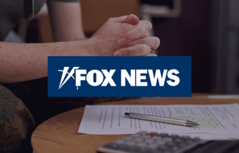 Clasped hands of a person wearing a military uniform resting above paperwork on a table, with a Fox News logo overlaid in the center.