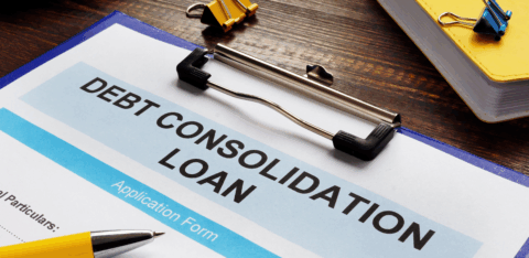Debt consolidation loan application form on a clipboard, with a pen, calculator, cash, and office supplies on a desk.