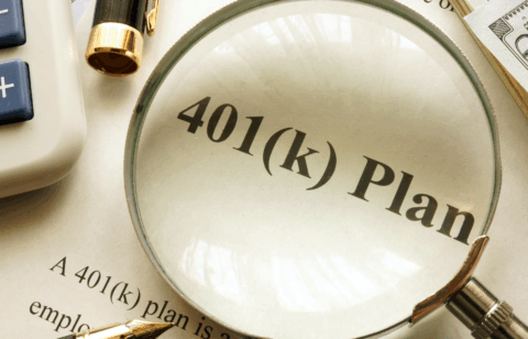 Magnifying glass highlighting the words “401(k) plan” on a printed document, with a calculator, pen, and cash nearby.